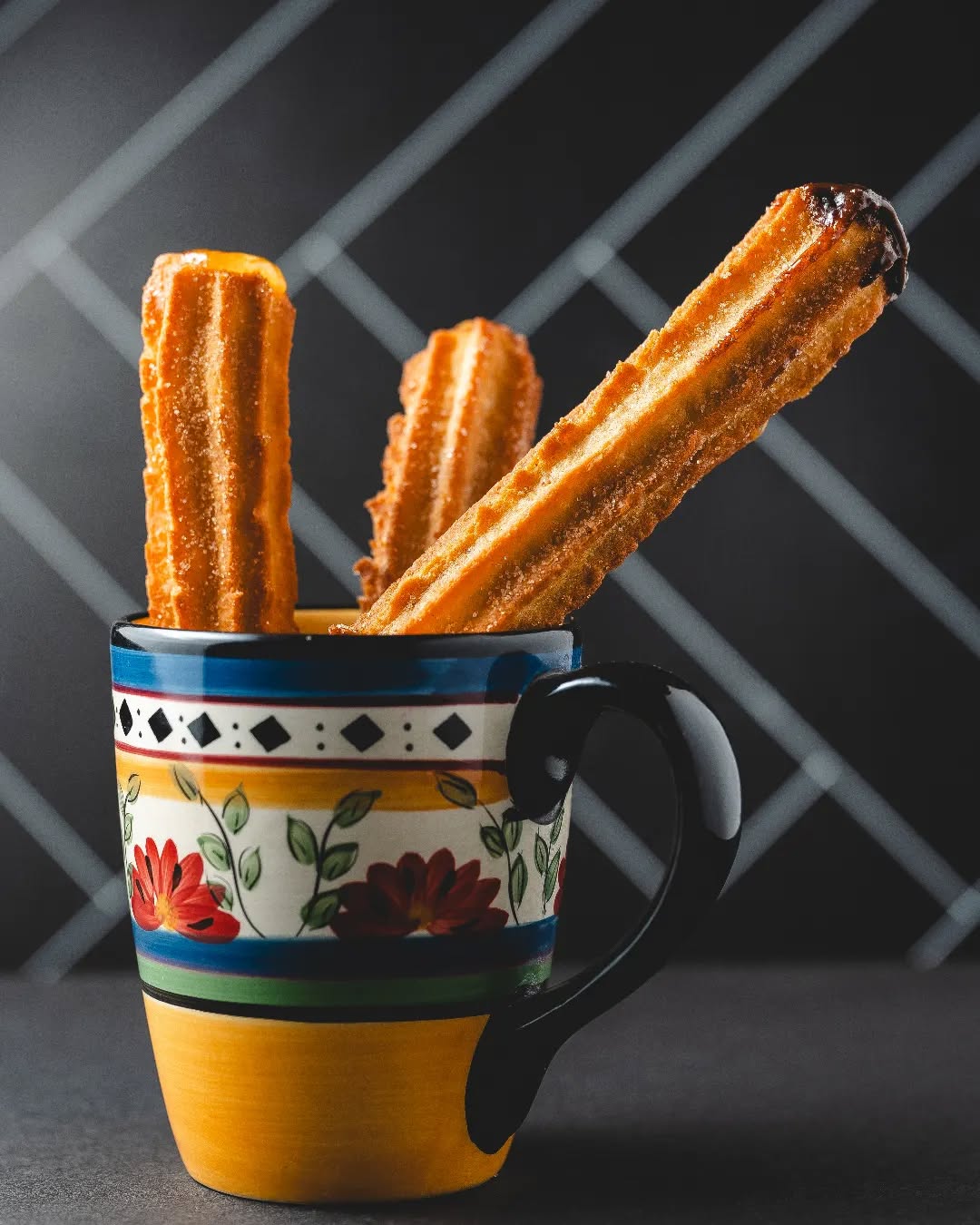 Churros servidos en una taza de cerámica pintada